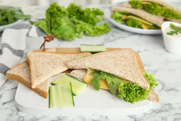 Tasty fresh sandwiches greens and cheese on white marble table, closeup