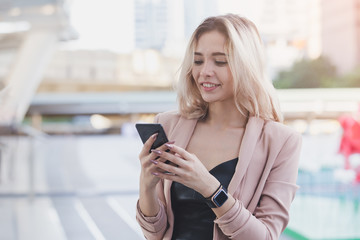beautiful blond hair using smartphone in city. business concept.