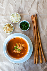 top view of seafood soup served with bread sticks and cubes, grated cheese, herbs