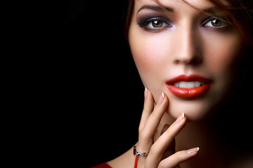 Close-up beautiful girl with bright evening party or prom make-up red lipstick isolated on a dark...