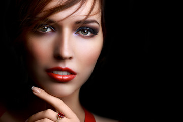 Fototapeta premium Close-up beautiful girl with bright evening party or prom make-up red lipstick isolated on a dark background