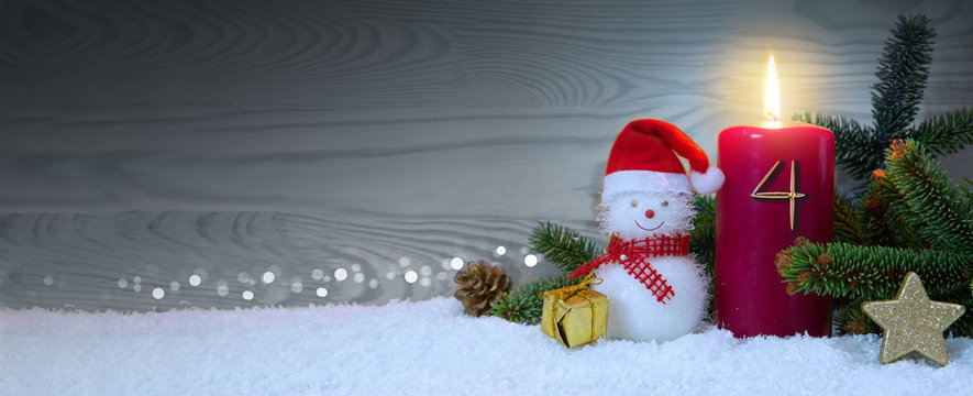 Christmas background with fourth Advent candle and Snowman with red decoration.