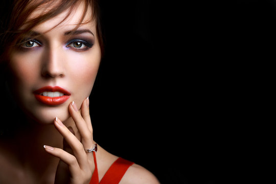Close-up beautiful girl with bright evening party or prom make-up red lipstick isolated on a dark background