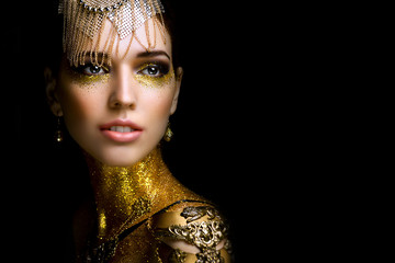 Beautiful woman portrait with golden glitter on her face. Girl with art make-up with golden...