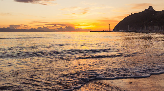 Sunrise over the beach of Poetto, Cagliari, soft waves, rocks and coastline