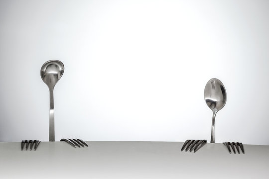 conceptual photography. Improvised stage. Image of a two people from spoon and forks, sitting at a table. Theme of food and restaurant business