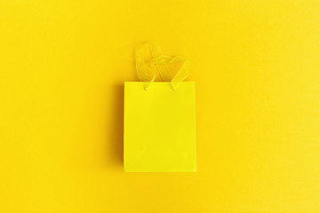 Minimal composition yellow colored with gift package mock up. Creative trendly concept for holiday, birthday greeting card. Top view and flat lay.