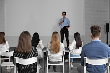 Male business trainer giving lecture in conference room with projection screen