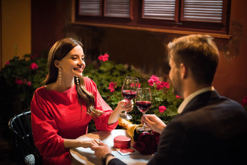 happy girl clinking glasses of red wine with boyfriend making marriage proposal in restaurant
