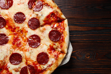 Hot delicious pepperoni pizza on wooden table, top view. Space for text