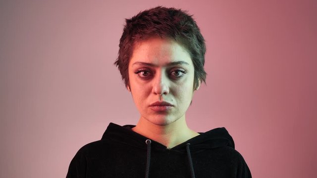Portrait of a short-haired teenager girl in neon rays. The girl looks directly at the camera 4k