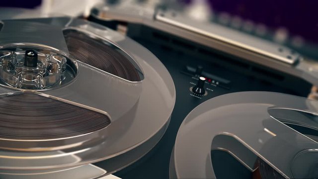 Closeup shot of spinning reels on old analogue reel-to-reel audio tape recorder  Rotation reel with tape. Loopable background for audio or voice listening. 4K UHD ProRes.