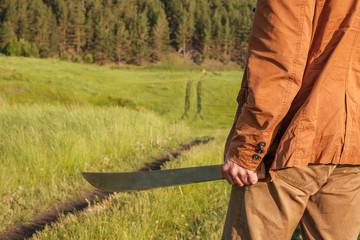 in the foreground a man in the hands of his sword the background is a field road and a forest