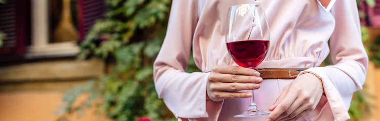 cropped view of woman holding glass of red wine, panoramic shot