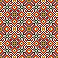 Seamless pattern in Christmas traditional colors. Repeated squares and rhombuses bright ornamental abstract background.