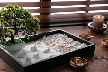 Beautiful miniature zen garden, candles and oil lamps on wooden table