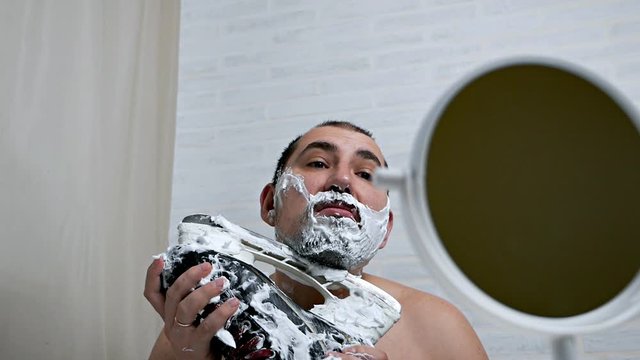 Heavy men's beard for shaving at home. A man shaves his beard with a hockey skate.Brutally shaving a beard