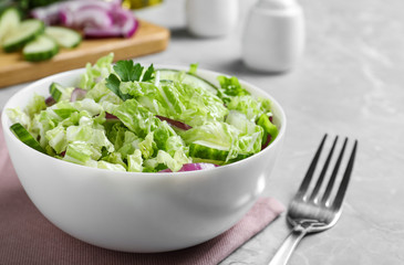 Tasty salad with cabbage and cucumbers on light grey marble table, closeup