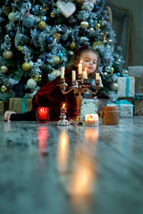 a little girl sitting in a room with Christmas decoration