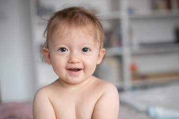 Portrait of a cute smiling baby in bedroom. Family morning at home.