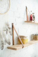 close up of dream catcher and wooden shelves with jars in kitchen