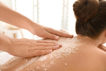 Obraz na płótnie Canvas Young woman having body scrubbing procedure with sea salt in spa salon, closeup