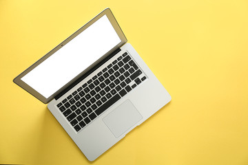 Modern laptop with blank screen on yellow background, top view