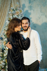 Young beautiful couple in love stands in a room decorated for the new year.