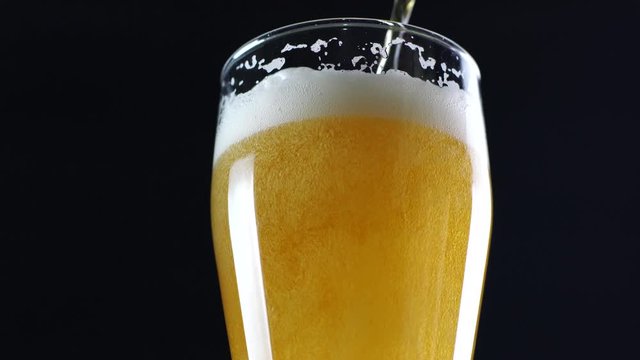 beer is pouring into a glass on black background