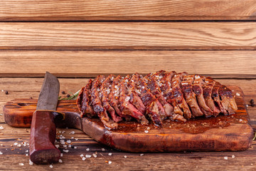 Chopped Grilled Steak Rib Eye on Rustic Cutting Board with Vintage Knife on Wooden Background. Juicy Medium Ribeye Steak with Salt, Pepper and Rosemary. Concept of Delicious Meat Food