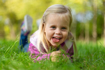 Cheerful little girl lying in the grass.