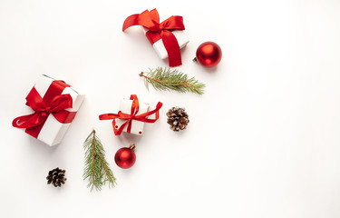 Christmas composition on a white background with white gift boxes, with a red ribbon with fir branches, toys, copy space for your congratulations