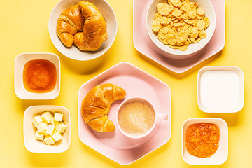 Coffee and croissants for breakfast on a yellow background