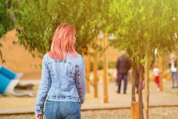 beautiful bright girl in casual style is walking at the beach. red-haired woman in jeans is walking on terrace