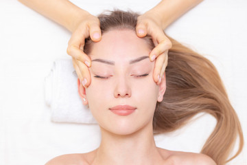 Young woman enjoying massage in spa salon. Face massage. Closeup of young woman getting spa massage treatment at beauty spa salon.Spa skin and body care. Facial beauty treatment.Cosmetology.