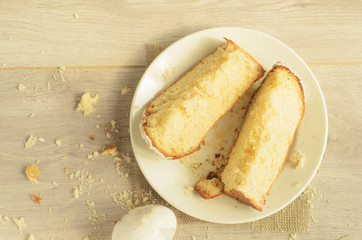 Holiday of Easter.Top view, slices of sweet Easter cake on a plate and One Easter egg on a light wooden background,copyspace in the left.