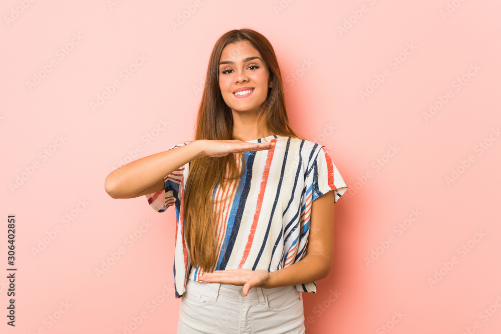 Wall mural Young slim woman holding something with both hands, product presentation.