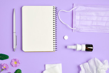 Flat lay concept of seasonal spring and summer pollen allergy with napkins, pills, face mask, pen, notepad, drops bottle and fresh flowers on purple background. Copy space, minimal style