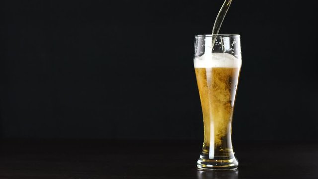 beer is pouring into a glass on black background
