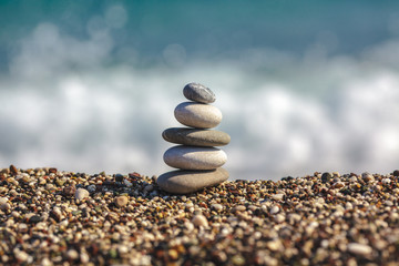 Stacked rounded stones at sea. Small polished pebbles stack on beach, blue smooth water of ocean in background