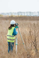 Back view of surveyor working with digital level in field