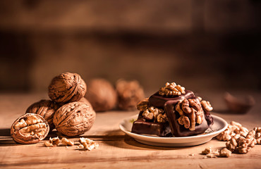 Dark chocolate pralines with walnut decoration and marzipan filling lying on a white porcelain plate. Christmas pralines with chocolate and walnuts. Confectionery, Confectioners concept.