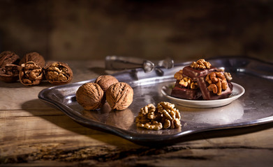 Dark chocolate pralines with walnut decoration and marzipan filling lying on a white porcelain plate. Christmas pralines with chocolate and walnuts. Confectionery, Confectioners concept.