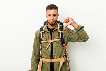 Young south-asian traveller showing a dislike gesture, thumbs down. Disagreement concept.