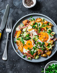 Potatoes, bacon, eggs breakfast baked hash on a dark background, top view. Delicious breakfast, snack, brunch - obrazy, fototapety, plakaty