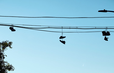 Silueta de zapatillas colgadas de un cable ante un cielo azul despejado en Nueva York
