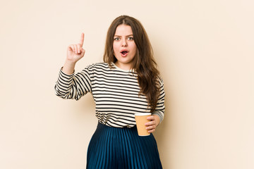 Young curvy woman holding a coffee having an idea, inspiration concept.