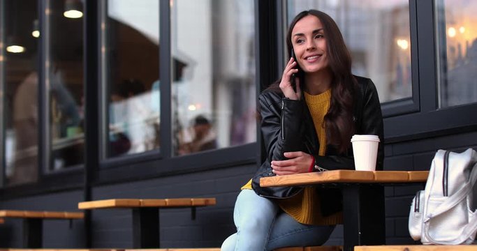 Beautiful young woman with phone in outdoor cafe. Space for text