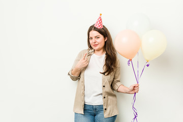 Young plus size curvy woman celebrating a birthday pointing with finger at you as if inviting come closer.