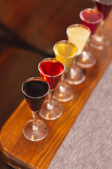many glasses of shot or liqueur. Friends drink shot or liqueur and cheers. alcohol on blurred table background. Party and toast concept.